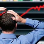 Stock Trader Clutching His Head in Front of a Screen Showing a Stock Market Crash